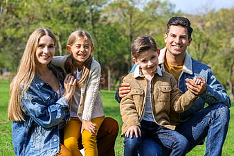 Happy family of four smiling together in a sunny park