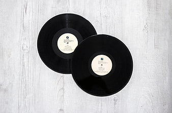 Two black vinyl records on white wooden background