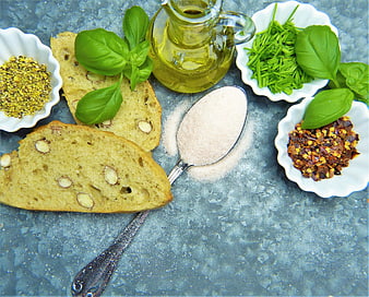 Flat lay of almond bread, olive oil, and fresh herbs on blue background