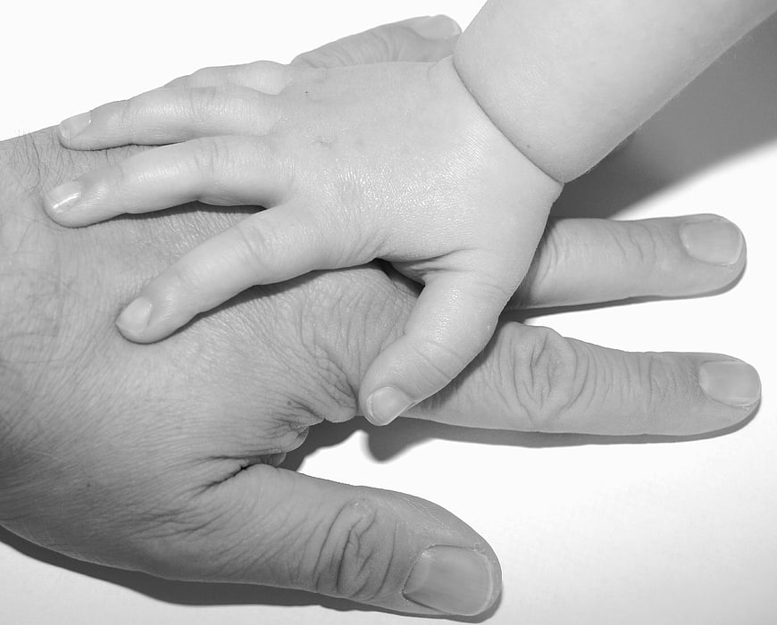 Black and white photo of baby hand on father's hand