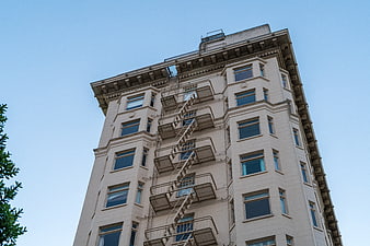 Low angle view of beige apartment building with fire escape