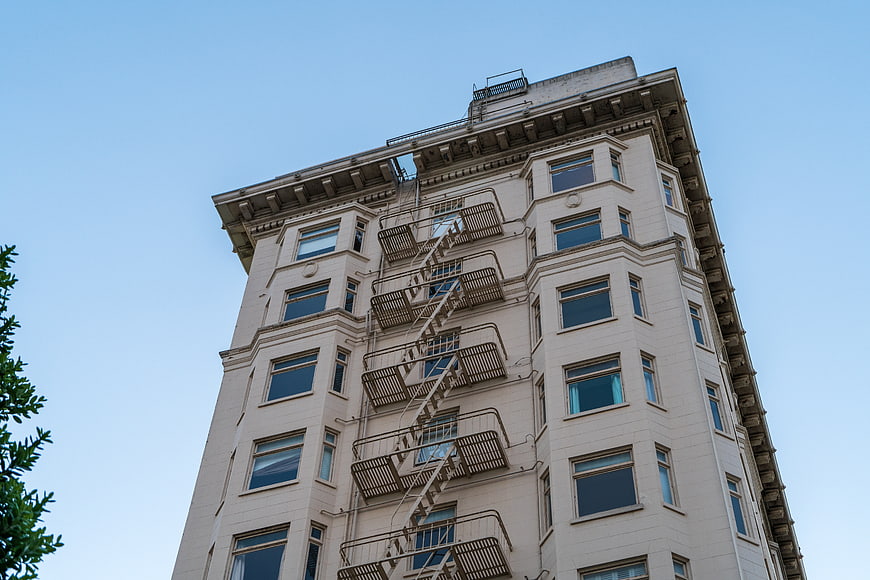 Low angle view of beige apartment building with fire escape