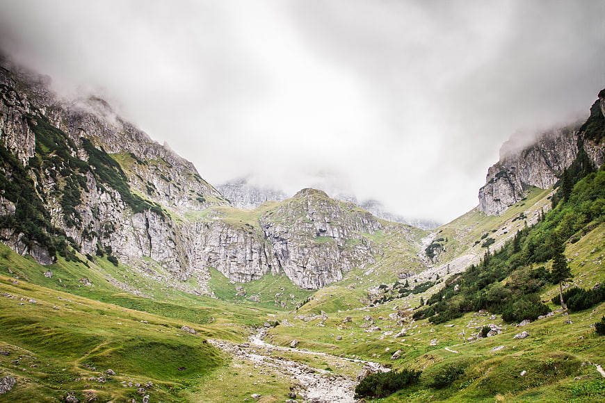 Misty Mountain Valley with Green Slopes and Rocky Peaks