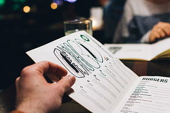 Hand holding burger menu in dim restaurant