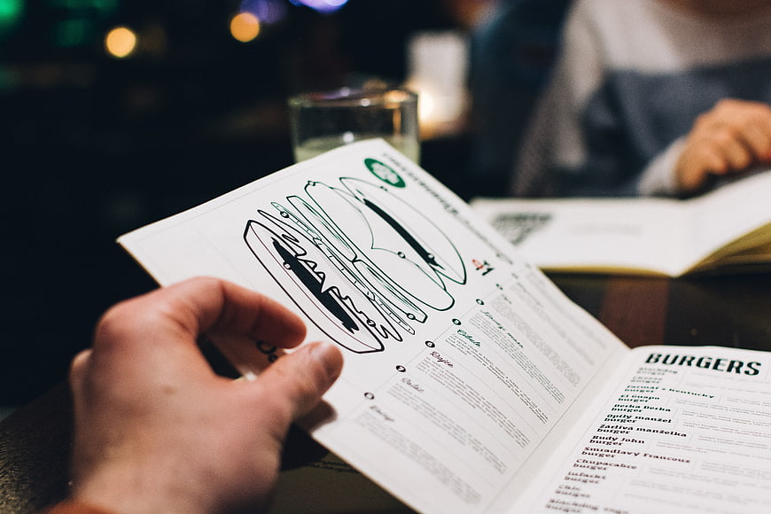 Hand holding burger menu in dim restaurant