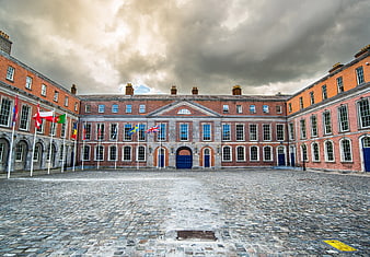 Historic Red Brick Courtyard with Cobblestones and International Flags