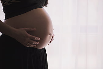 Pregnant woman holding belly by window
