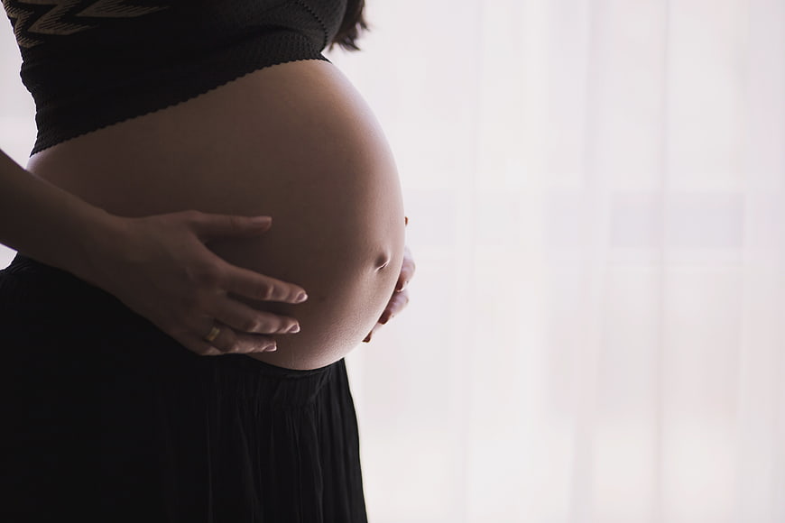 Pregnant woman holding belly by window