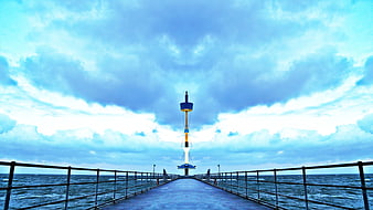 Blue pier leading to lighthouse under dramatic cloudy sky
