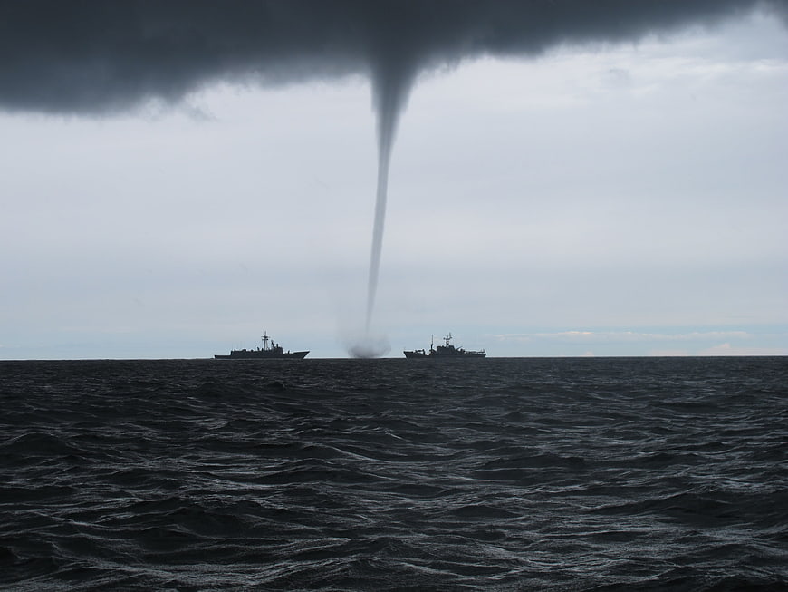 Dramatic Waterspout Over Ocean with Two Warships