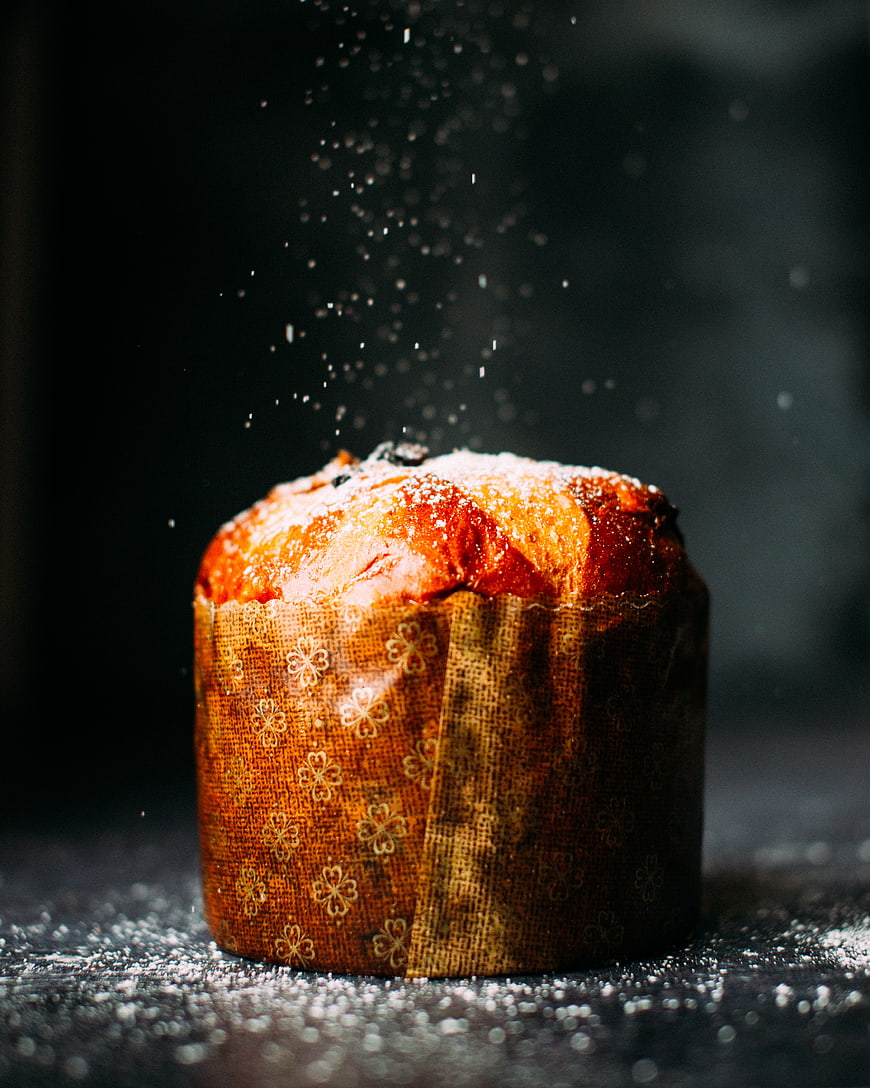 Panettone dusted with powdered sugar on dark background