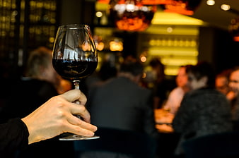 Hand holding red wine glass in restaurant
