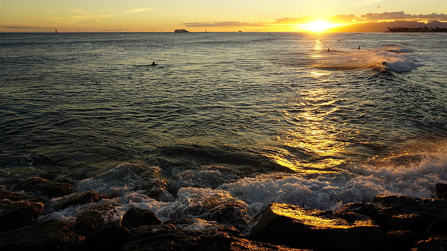 Golden Sunset Over Ocean Waves Crashing on Rocks