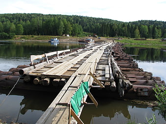 Rustic wooden pontoon bridge crossing a calm river in summer