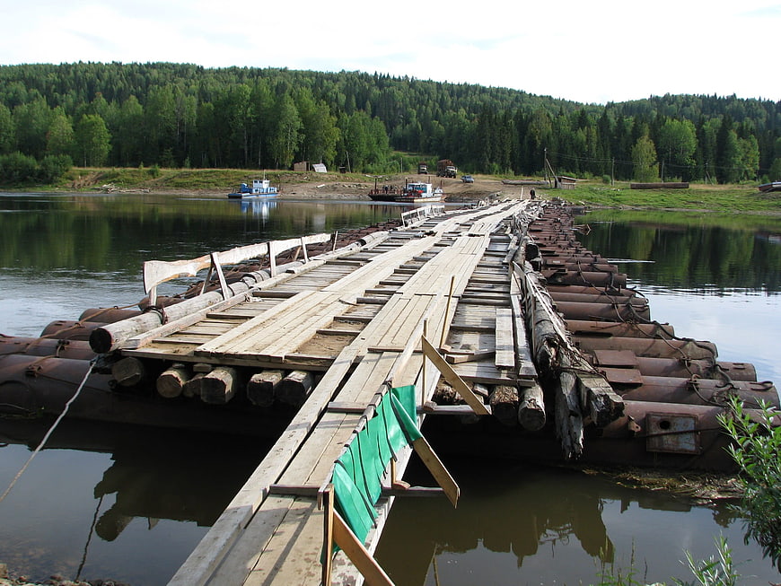Rustic wooden pontoon bridge crossing a calm river in summer
