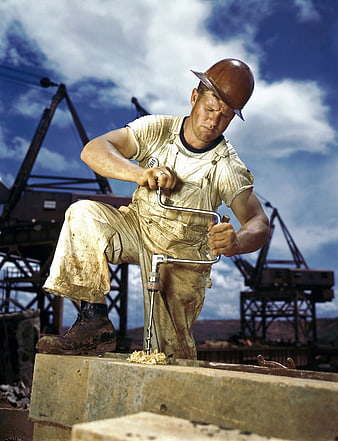 Hardworking construction worker drilling steel beam outdoors