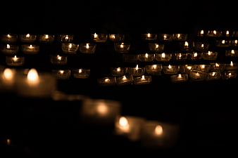 Rows of lit tea light candles in dark church setting