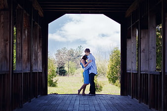 Couple embracing inside a rustic wooden covered bridge