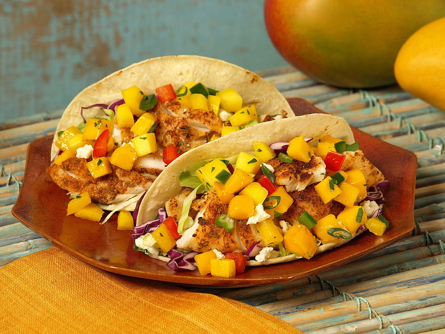 Grilled fish tacos with fresh mango salsa on rustic plate