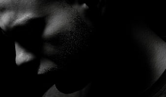 Dramatic black and white close-up of a man's face in shadow