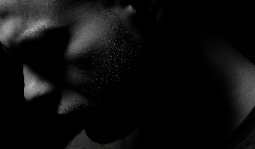 Dramatic black and white close-up of a man's face in shadow