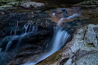 Long exposure stream flowing over dark rocks