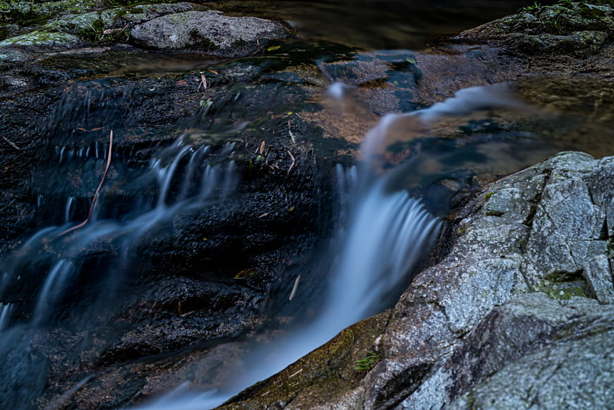 Long exposure stream flowing over dark rocks