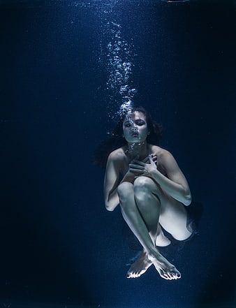 Underwater Portrait of Woman with Air Bubbles in Dark Blue Water