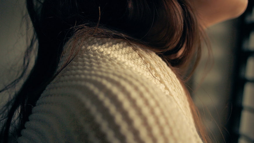 Close-up of woman in cream knit sweater with sunlight