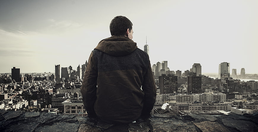 Man sitting on rooftop overlooking city skyline