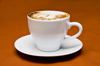 White Cup of Cappuccino with Cocoa Powder on Orange Background