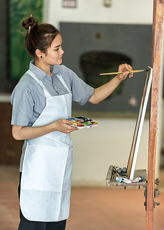 Young female artist painting on canvas in a bright studio