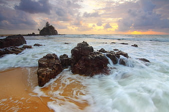 Dramatic Sunset Over Rocky Beach with Long Exposure Waves