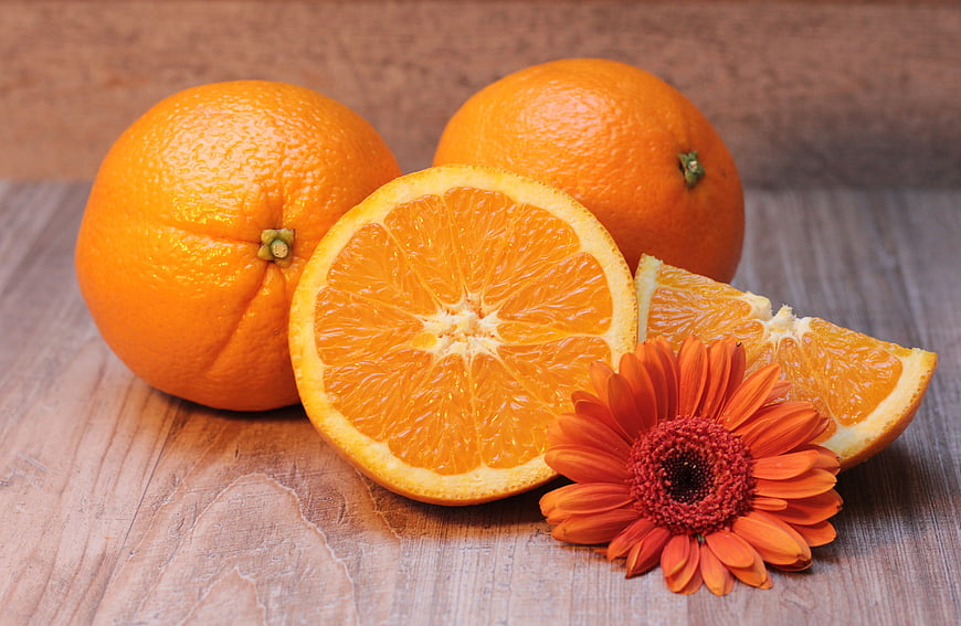 Fresh Oranges and Gerbera Daisy on Wooden Table
