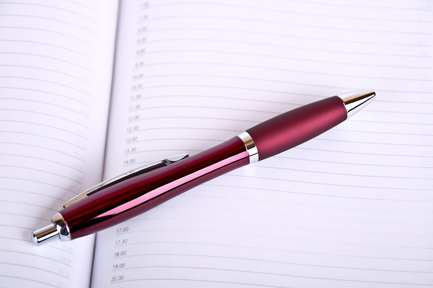 Red Ballpoint Pen On Open Planner Schedule