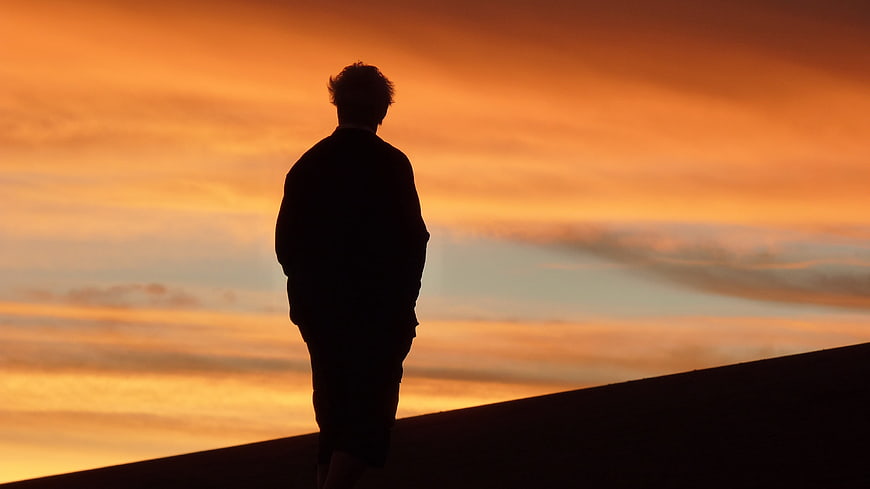Silhouette of Man Standing Against Vibrant Orange Sunset Sky