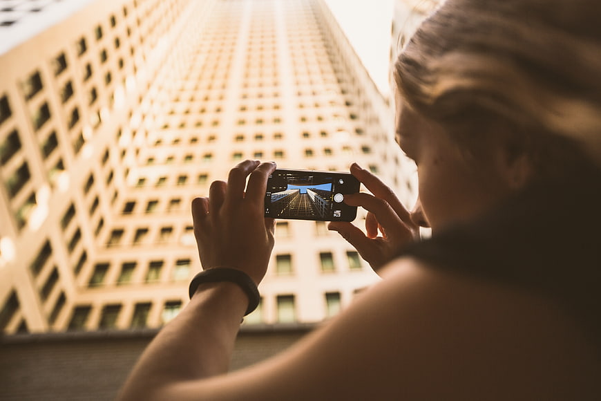 Woman taking photo of skyscraper with smartphone