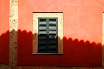 Red wall with green shutters and scalloped shadow