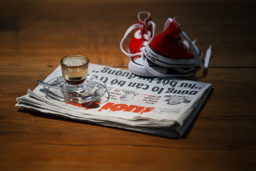 Red sneakers and coffee on newspaper
