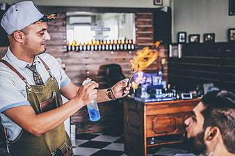 Barber using flame to style beard in vintage shop