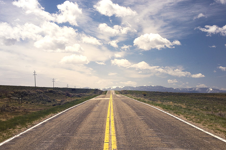 Long straight highway stretching to distant snow-capped mountains
