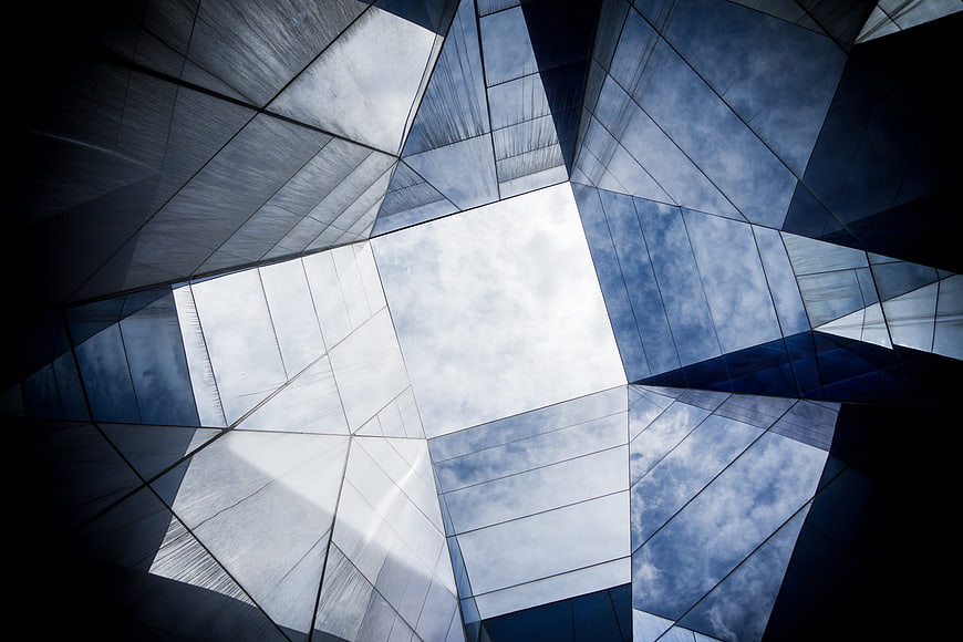 Low angle view of modern glass skyscraper reflecting clouds