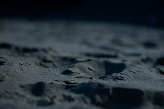 Close-up of dark wet sand texture with shallow depth of field