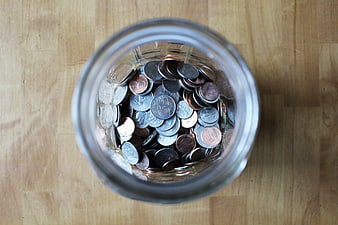Top-down view of a glass jar filled with US coins on a wooden table