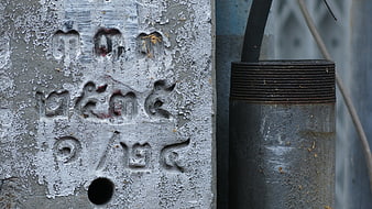 Close-up of weathered concrete utility pole with Thai script