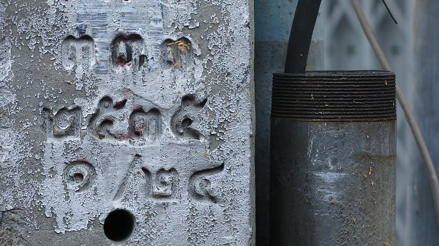 Close-up of weathered concrete utility pole with Thai script