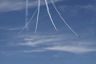 Four aerobatic jets flying in formation with smoke trails
