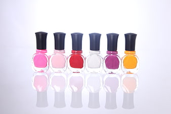 Colorful nail polish bottles lined up on white background
