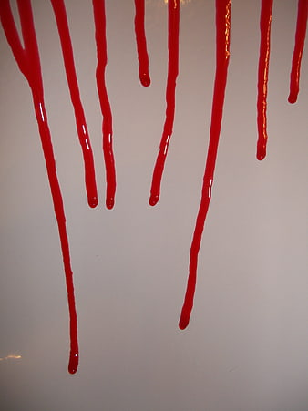 Red liquid dripping down a white wall background