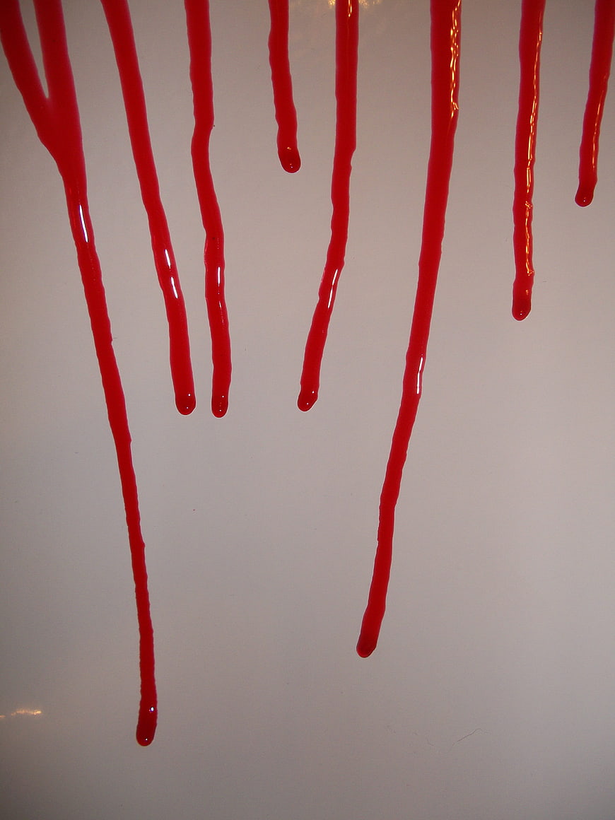 Red liquid dripping down a white wall background